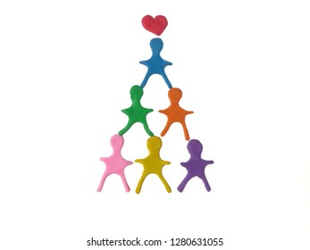 Colorful children model connect themselves as pyramids made from plasticine clay on white background, the top is a red heart dough, harmony leading to success. - Powered by Shutterstock