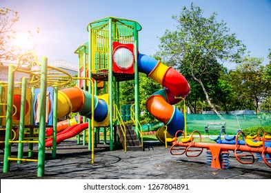 Colorful children playground,exercise kid,activities in outdoor public park surrounded by green trees at sunlight morning.Children run, slide,seesaw on modern playground.Funny toy land for child