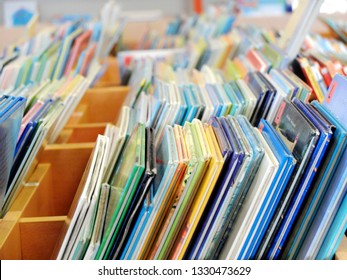 A Lot Of Colorful Children's Books Standing On The Public Library Shelf.