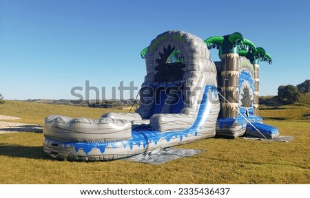 Colorful children's bounce house with slide in field with palm trees