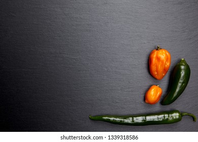 Colorful chili peppers on dark stone plate