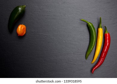 Colorful chili peppers on dark stone plate