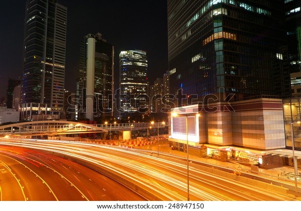 Colorful city night scene with modern\
skyscrapers and cars motion blurred in Hong Kong,\
Asia.