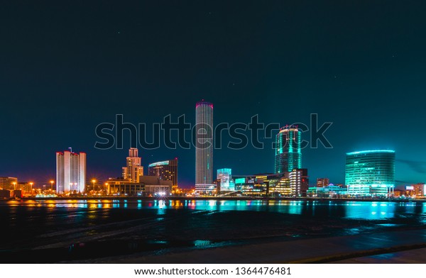 Colorful cityscape of Yekaterinburg modern building\
at night reflecting in\
water