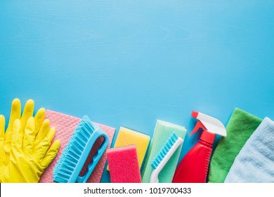 Colorful cleaning set for different surfaces in kitchen, bathroom and other rooms. Empty place for text or logo on blue background. Cleaning service concept. Early spring regular clean up.