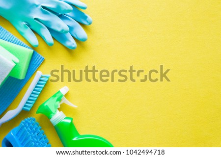 Colorful cleaning set for different surfaces in kitchen, bathroom and other rooms. Empty place for text or logo on yellow background. Cleaning service concept. Early spring regular clean up. Top view.