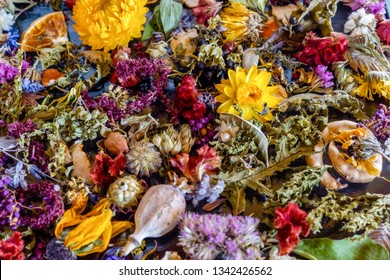 A colorful closeup of dried flowers, dried oranges, fragrant herb leaves, and seedpods used as flower confetti or potpourri