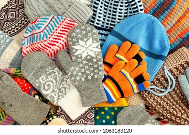 Colorful clothes in the form of hats, mittens and gloves. Clothes for autumn and winter. Hats, mittens and gloves are piled in a pile. Warm clothes background.
