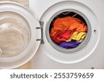 Colorful clothes inside washing machine with open door. laundry close up.