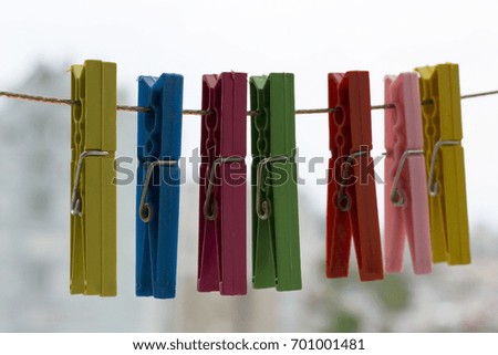 Colorful clothespins hanging on rope on a city background