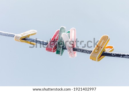 Colorful clothespins on clothesline covered with snow outdoors. Winter scene, housework concept