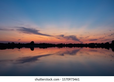 Colorful clouds after sunset, mirror reflection in lake water