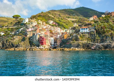 The colorful coastal and hillside village of Riomaggiore, Italy, on the Ligurian coast of the Cinque Terre in early autumn with aqua blue sea.