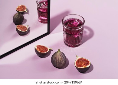 Colorful cocktail garnished with figs. Cocktail purple color garnished with figs, frontal view. On a pink background