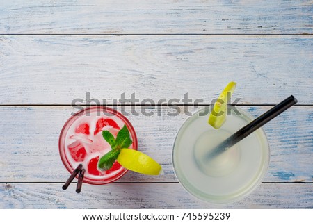 Colorful cocktails. Red Cocktail with ice and lime, Margarita on wooden table top view.