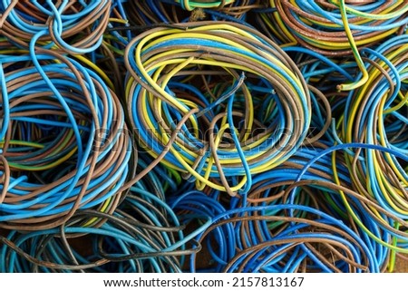 Colorful, coiled copper cables in rubber sheaths. Prepared for further recycling, copper recovery. Cables texture in full screen