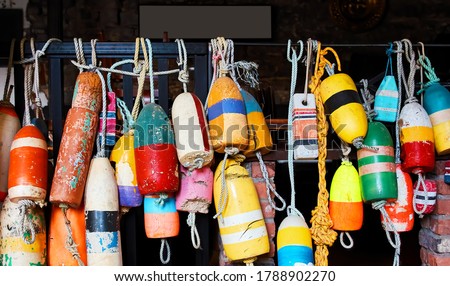 Colorful concrete anchors or buoys with ropes decoratively hanging on a metal bar 