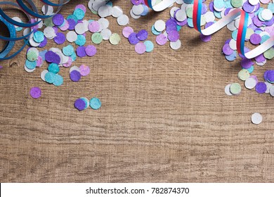 Colorful Confetti And Serpentine Spread Over Wooden Table. Cool Colors: Blue, Purple And Aqua. Carnival Party Background Concept. Space For Text, Copyspace.