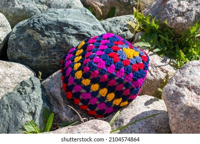 A colorful craft crocheted pillow, multicolored; red, purple, blue, and yellow color cotton wool. The textile pattern in the handmade pillow is a flower with six sides and tidy stitches. 