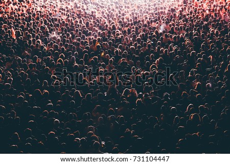Colorful crowd of people of a big music festival in a stage lights as a beautiful background