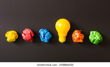 Colorful crumpled paper ball with yellow light bulb against black background.  - Shutterstock ID 1938866920