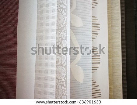Colorful curtain samples hanging from hangers on rail in a display retail store Multi color fabric texture samples selection of fabrics for interior decoration Curtains,tulle and furniture upholstery