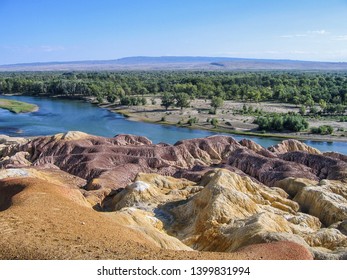 Colorful Danxia lanform near river and forest in Xinjiang, China