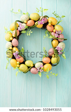Colorful decorative Easter eggs wreath on light blue wooden background