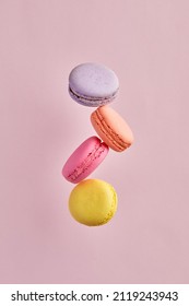Colorful delicious French dessert macaron or macaroons flying or falling in motion on pink background.