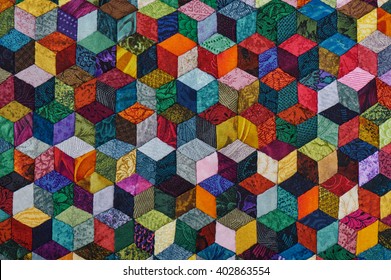 Colorful detail of quilt sewn from diamond pieces has view like three-dimensional