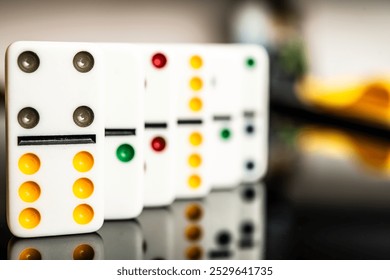 Colorful dominoes on a reflective surface, representing fun, strategy, and classic board games for social gatherings and family entertainment. - Powered by Shutterstock