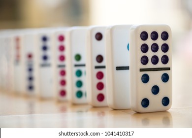 Colorful dominoes set up on a wooden floor

