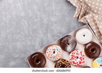 Colorful Donuts Box On Stone Table. Top View With Copy Space