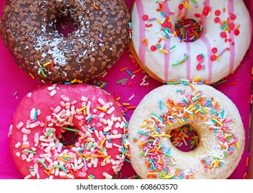 Colorful Donuts In Box On Wooden Table. Top View With Free Copy Space.