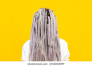 colorful dreadlocks and braids of a girl on a yellow isolated background back view, close-up of a woman's unique hairstyle - Powered by Shutterstock