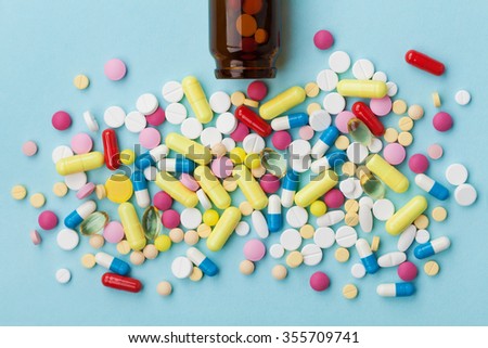 Colorful drug pills on blue background, pharmaceutical concept