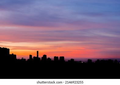 Colorful Dusk Sky In Evening With Silhouette Of Many Building In City.