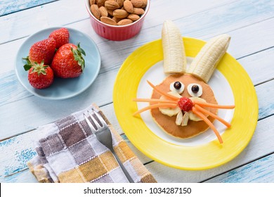 Colorful Easter breakfast for kids. Easter Bunny food art on yellow plate. Top view