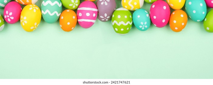 Colorful Easter Egg top border over a soft green paper banner background. Copy space.