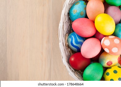 Colorful Easter Eggs In A Basket On Wooden Background