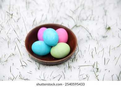 Colorful Easter Eggs in a Bowl on Snowy Ground with Green Grass - Powered by Shutterstock