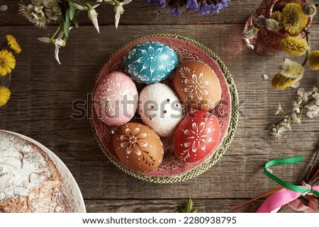 Colorful Easter eggs decorated with wax with spring flowers and mazanec - traditional Czech sweet pastry similar to hot cross bun