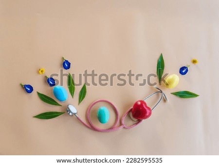 Colorful  Easter  eggs ,medical  stethoscope , red  heart  shape  and green  leaves  on  pastel  background . Top  view and  copy  space  for  use .