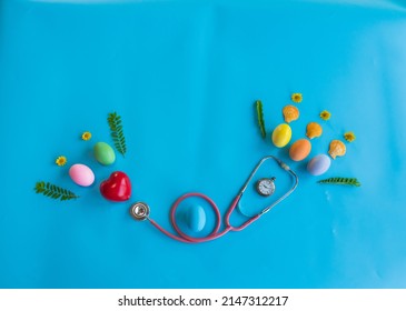 Colorful  Easter  Eggs , Red  Heart  Shape , Medical  Stethoscope  And  Green  Leaves  On  Blue  Background  For The  Health  Concept. Top  View