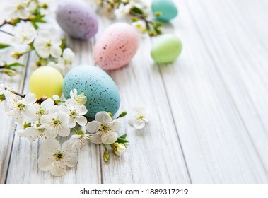 Colorful Easter eggs with spring blossom flowers over wooden background. Colored Egg Holiday border.