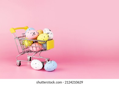 Colorful easter quail eggs in shopping cart on pink background. Copy space. Minimal Easter concept.