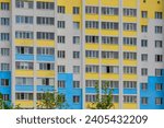 It is a colorful European apartment building in sunny day. It is multicolored city buildig iThere are clouds in blue sky.