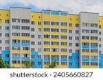 It is colorful European apartment building in sunny day. It is multicolored city buildig. There are clouds in blue sky. It is close up view of the building