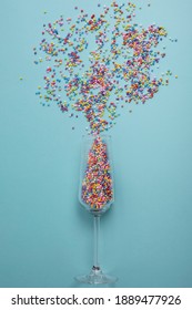 colorful explotion from champagne glass with blue background. Simple concept 