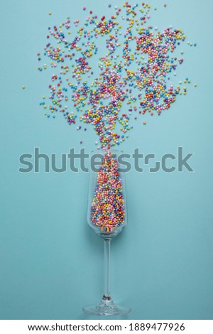 colorful explotion from champagne glass with blue background. Simple concept 